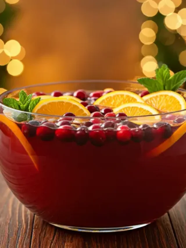 A festive berry and citrus punch in a glass bowl, garnished with fresh berries, orange slices, and mint leaves, radiating vibrant holiday cheer. Jolly Berry Citrus Punch