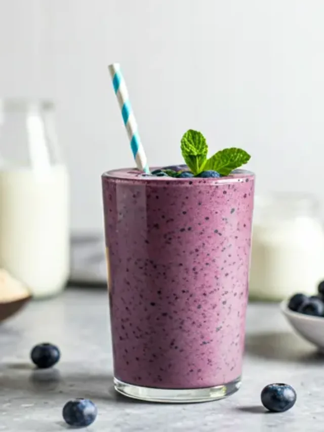 A rich purple smoothie in a glass, topped with fresh blueberries, chia seeds, and a drizzle of almond butter, exuding health and vitality. Antioxidant Packed Blueberry Bliss Protein Smoothie .