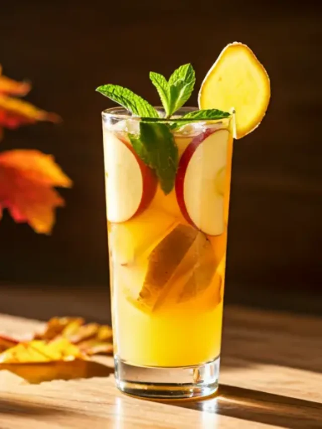 A cozy glass of Autumn's Delightful Elixir , featuring a rich amber hue, garnished with a cinnamon stick, a dried orange slice, and a sprinkle of nutmeg.