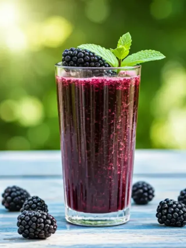 A deep purple glass of Berry Enchantment: A Blackberry Symphony, garnished with fresh blackberries and a sprig of mint.