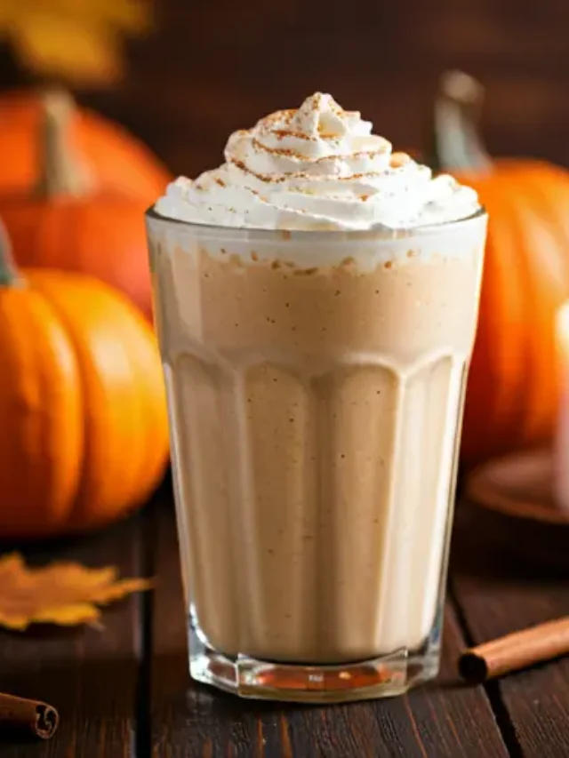 Creamy Pumpkin Spice Delight : A creamy orange-hued pumpkin smoothie in a glass, topped with whipped cream and a dusting of cinnamon, exuding warm autumnal charm.