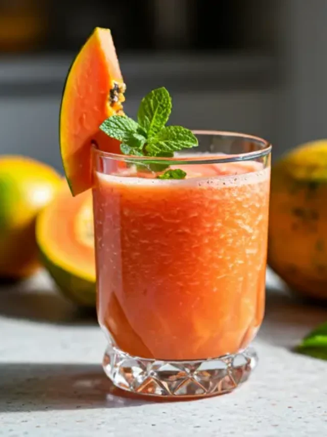 Exotic Papaya Bliss Juice : A vibrant orange papaya juice in a glass, garnished with a fresh papaya slice and a sprig of mint.