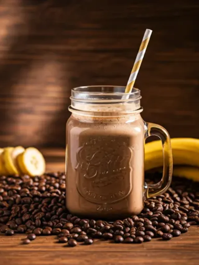 Morning Mocha Bliss Smoothie : A creamy morning mocha smoothie in a glass, topped with a dusting of cocoa powder.
